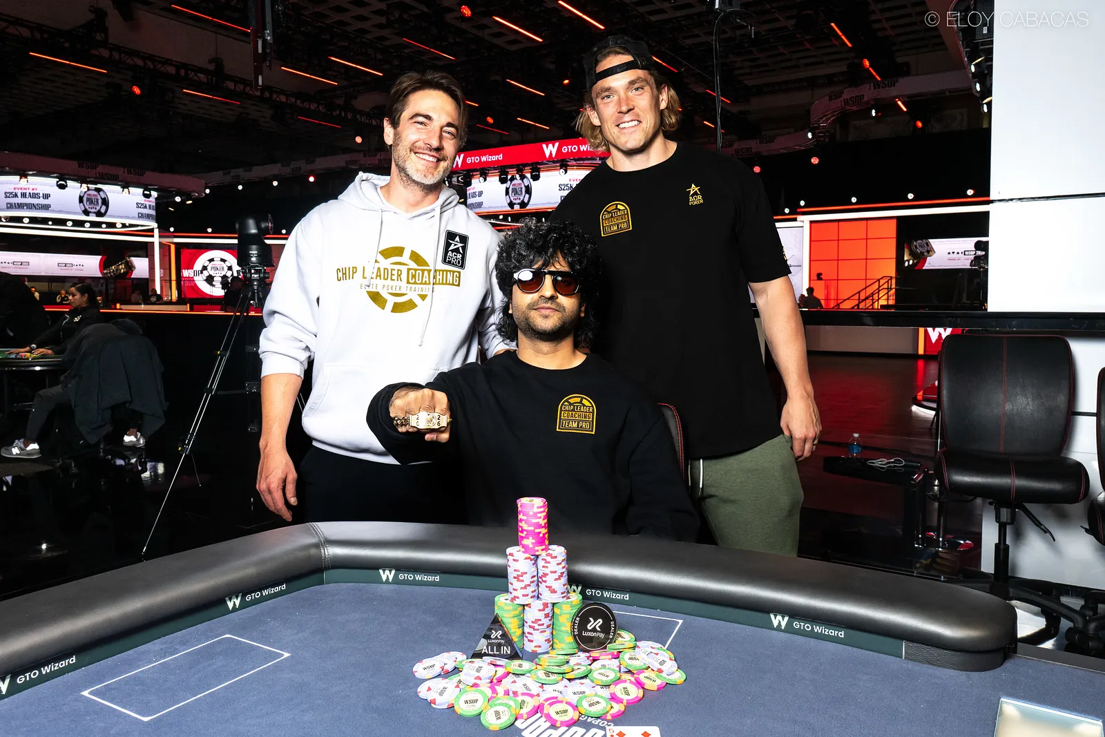Daniyal Gheba displays his WSOP bracelet with Chance Kornuth and Alex Foxen behind him.